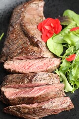 Pieces of delicious grilled beef meat and greens on plate, closeup