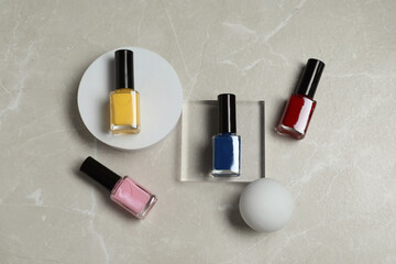 Flat lay composition with bright nail polishes in bottles on light textured table