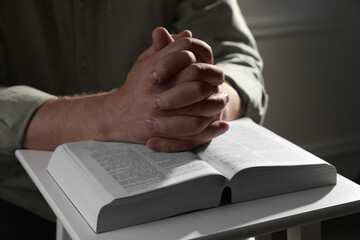 Obraz premium Religion. Christian man praying over Bible indoors, closeup