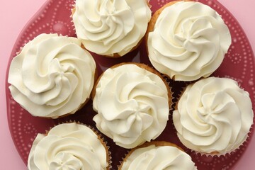 Tasty vanilla cupcakes with cream on pink background, top view