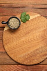 Cutting board, cumin and parsley on wooden table, top view. Space for text