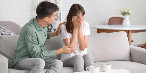 Obraz premium Young man trying to make peace with wife after quarrel at home