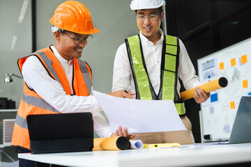 Architects or engineer holding pen pointing equipment architects on laptop with on on architectural project at construction site at desk in office.