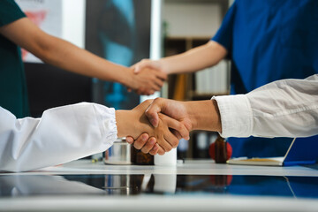 Doctors shaking hands, working together as a team at the hospital.