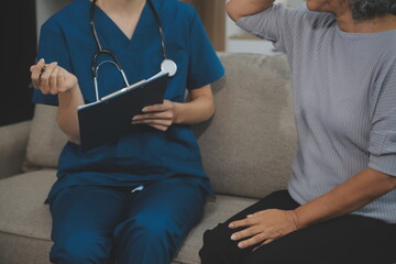 Female caregiver doing regular check-up of senior woman in her home.