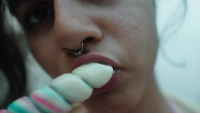 Close-up of a woman enjoying a colorful popsicle, intimate and vibrant, with a shallow depth of field