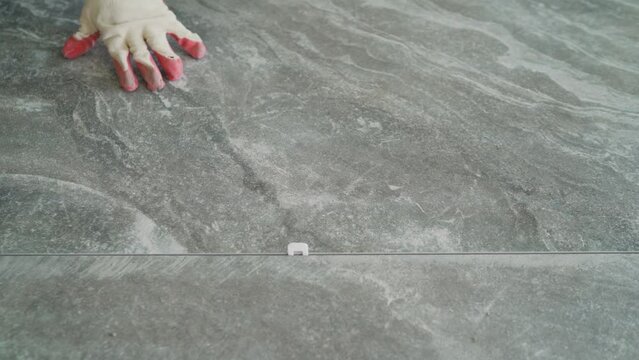 Installing a large ceramic tile. Worker laying floor tiles. Laying large ceramic tiles on the floor.