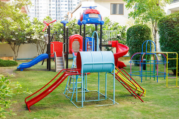 playground colorful fun exciting machine, small kids children play area in backyard green grass filed in the city - 807762921