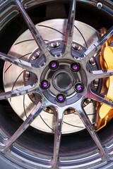 Close-up of a car shiny, stylish, designer alloy wheel with purple rivets.