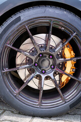 Front view of a car tire and its stylish, designer alloy wheel with purple rivets.