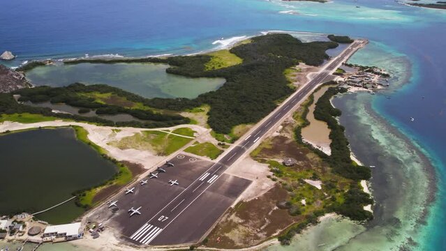 The narrow runway on erera los roques with clear blue waters, aerial view