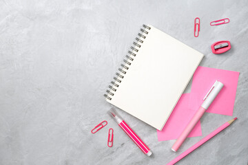 Notebook and pink sticky note and stationery on stone texture background. Work desk space