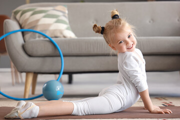 Cute little girl doing gymnastics on mat at home