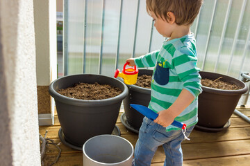 A boy planting seeds and watering the soil in the slides in the greenhouse