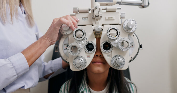Eye care, medical and child in clinic, patient and hand of specialist, phoropter or refractor for girl. Healthcare, technology and machine for help for kid, exam and vision for check up in hospital