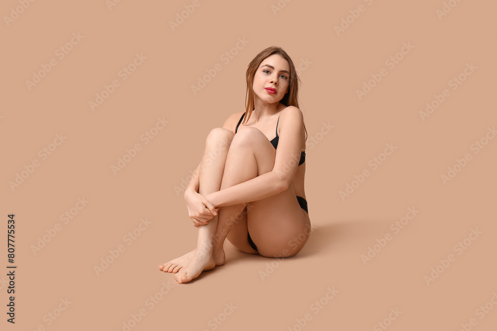 Poster Attractive young woman in black underwear sitting against beige background