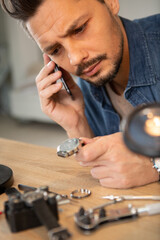 man on the phone while fixing a watch