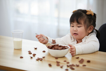chubby child girl enjoy eating chocolate cereal on the table