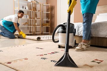 Female janitor cleaning carpet in bedroom