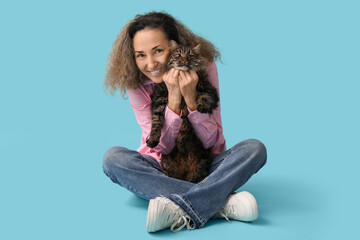 Mature woman with cute cat sitting on blue background