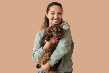 Happy mature woman with cute cat on brown background