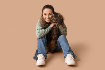 Mature woman with cute cat sitting on brown background