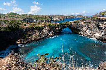 Obraz premium Natural stone bridge over sea pool in Broken Bay beach in Nusa Penida island. Popular Bali travel destination.