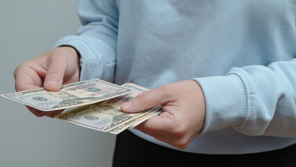 A woman gives paper American dollar bills. Cash. Pay someone with dollars. Bribery and corruption concepts