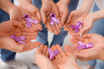 Fototapeta premium People with lavender awareness ribbons on light background, closeup. World Cancer Day