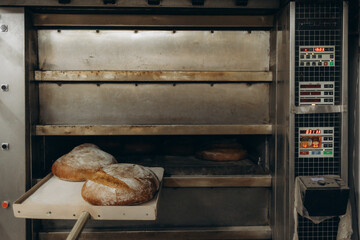 Baker putting bread in the bakery oven cowering on the floor of the bakery