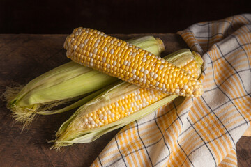 Several cobs sweet corn on wooden background..