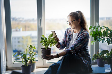 An attractive Caucasian woman identifying a green plant using an application in Smartphone. Caring...