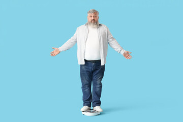 Overweight mature shocked man with scales on blue background. Weight loss concept