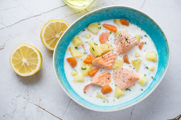 Lohikeitto or finnish soup with salmon in a turquoise bowl, horizontal shot on a white granite background, elevated view