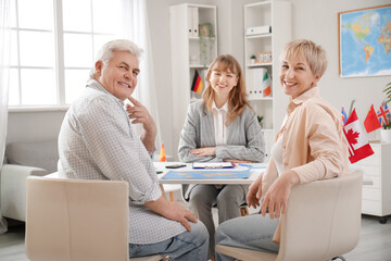 Fototapeta premium Mature couple with travel agent sitting at table in office