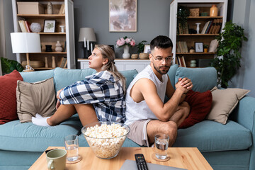 Communication problems, relationship difficulties. Young couple man and woman sitting on sofa at...
