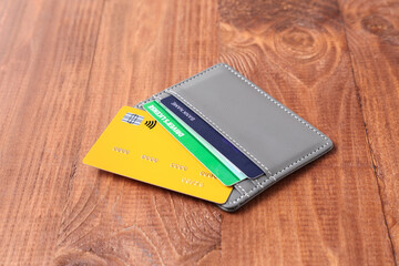Grey holder with credit cards and driver's license on wooden background, closeup