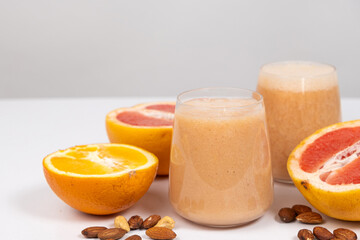 Fruit smoothie in a glass, grapefruit and orange on white background.