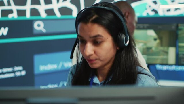 Indian woman dispatch operator gives directions to couriers, avoiding traffic by monitoring radar CCTV surveillance footage. Employee uses gps coordinates and satellite map. Camera A.