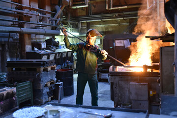 young worker in protective clothing at work at the blast furnace in an iron foundry