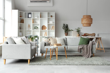 Comfortable sofas, shelving unit and coffee table with books in living room