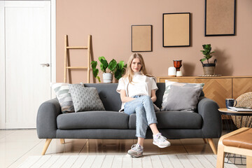 Young woman sitting on sofa in stylish living room