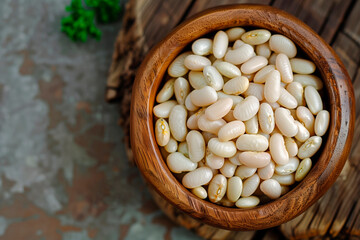 White beans in a wooden bowl. Textured surface