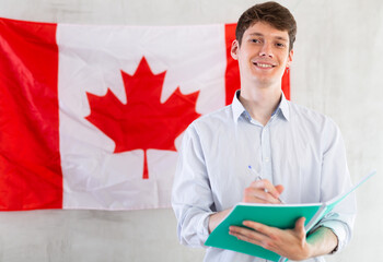 Young guy makes notes against background of Canada flag