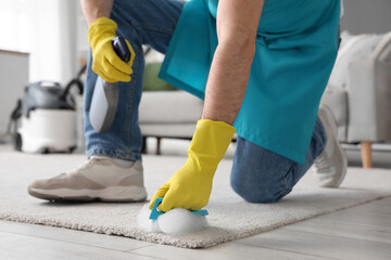 Male janitor cleaning carpet with brush in room, closeup