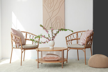 Chairs and coffee table with vase and blooming branches in living room