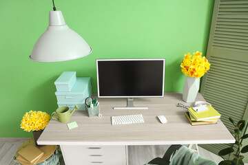 Interior of stylish office with workplace and daffodils in vases