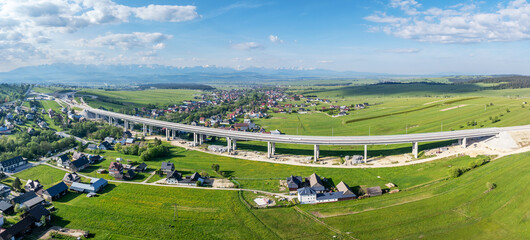 Fragment of highway under construction on Zakopianka road, Poland, over Klikuszowa village, main place of traffic jams. State May 2024. Tatra Mountains in background. Wide aerial panorama