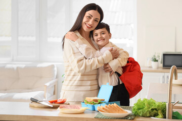 Happy mother with her little son hugging before school in kitchen