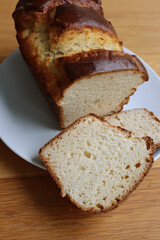 Homemade baked and sliced  Brioche Bread on a white plate on wooden table